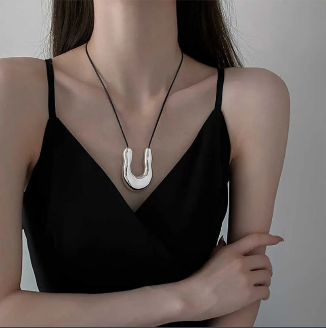 Punk style U-shaped pendant necklace with a horseshoe design on an adjustable leather rope. Unisex and perfect as a bold sweater chain.